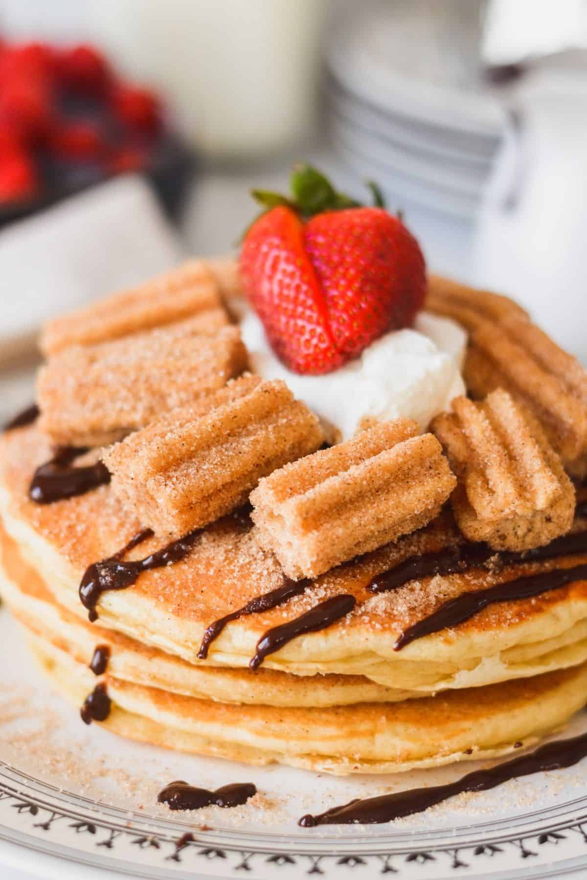 Churro pancakes smothered in cinnamon sugar, cinnamon chocolate sauce, whipped cream and churro bites.