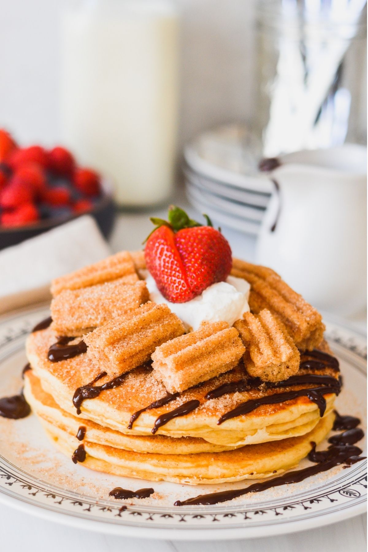 Churro Pancakes are brushed with melted butter, cinnamon sugar and drizzled with a cinnamon chocolate sauce and churro bites.