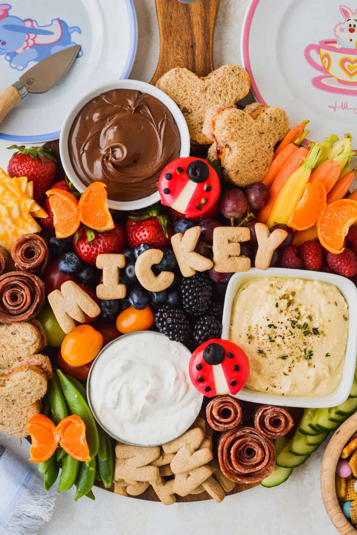 Mickey themed charcuterie board for kids.  Fresh veggies, fruits, salami and cheese.