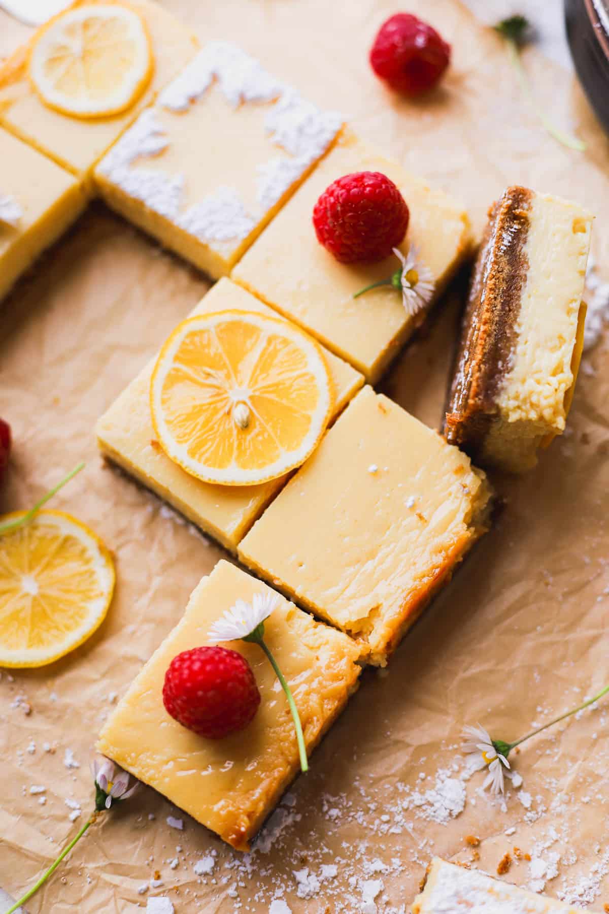 Baked Meyer lemon bars garnished with lemon slices and fresh raspberries. 