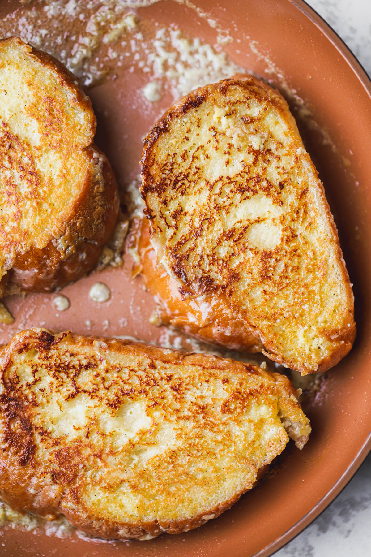 Custard French toast cooked inside a hot skillet with melted butter.