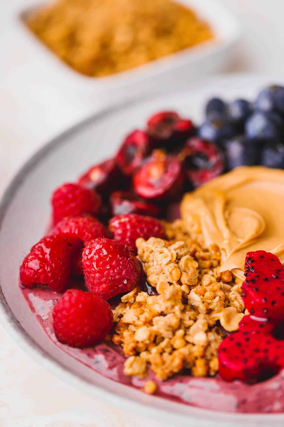 Peanut butter acai bowl with fresh raspberries, peanut butter granola, smooth peanut butter and mickey shaped dragon fruit.