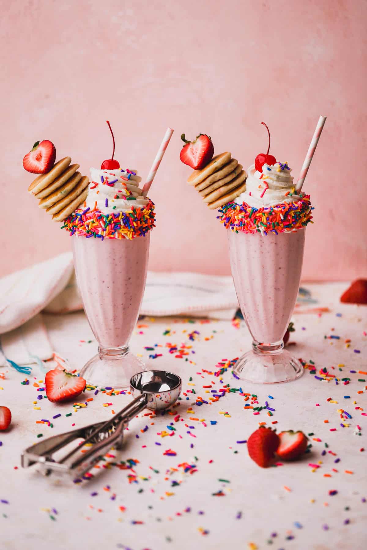 Strawberry and banana milkshake topped with whipped cream, funfetti pancakes, sprinkles and maraschino cherry.