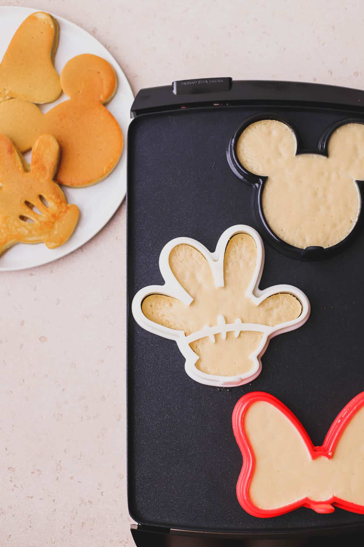 Mickey Biscoff pancakes cooked on a griddle.