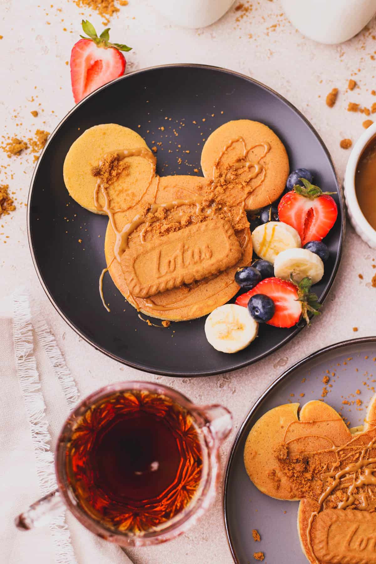 Individual Mickey and Minnie pancakes cooked inside silicone molds and drizzled with biscoff spread and crushed cookies.  