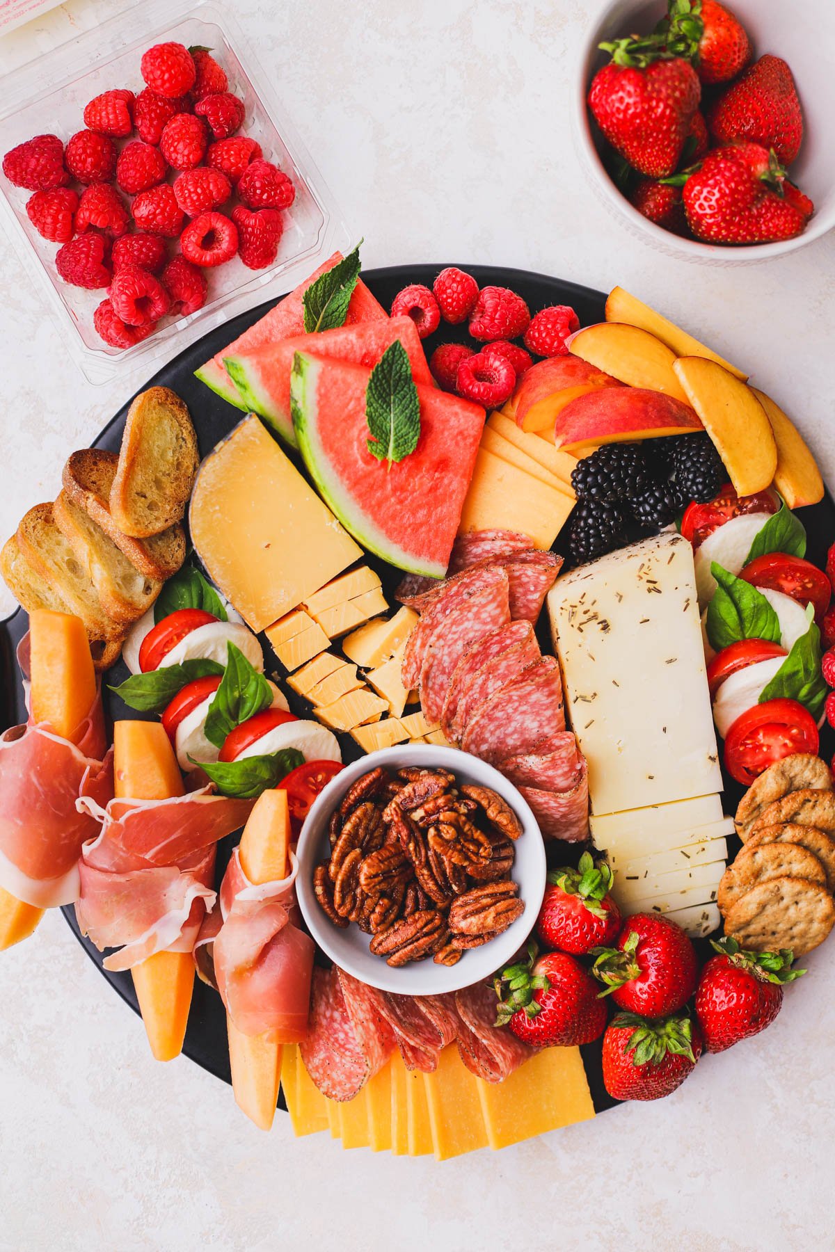 Watermelon, peaches, berries, crackers and nuts added to this summer charcuterie board.