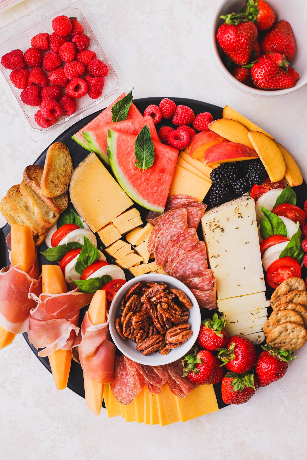 Watermelon, peaches, berries, crackers and nuts added to this summer charcuterie board. 