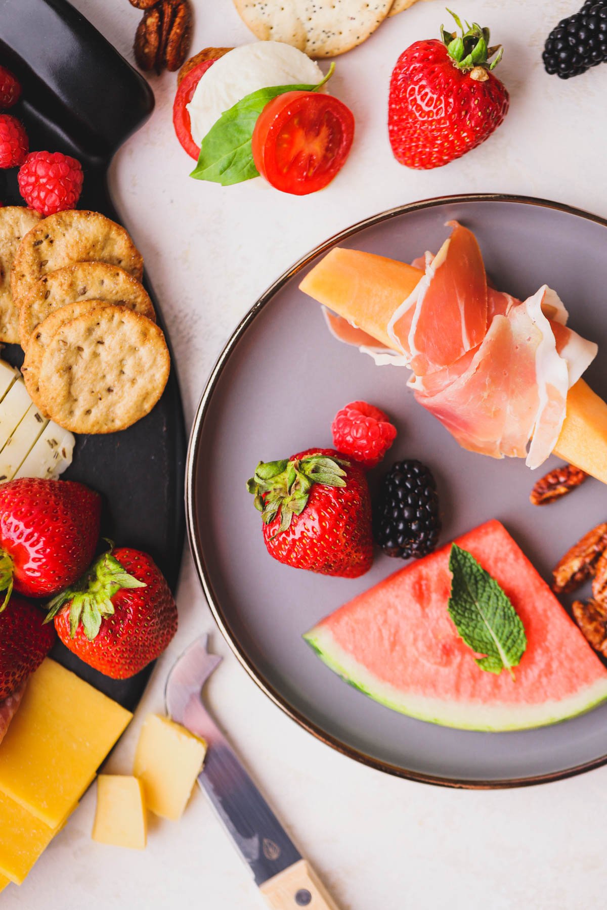 Sliced watermelon, prosciutto wrapped cantaloupe and fresh berries with crackers.