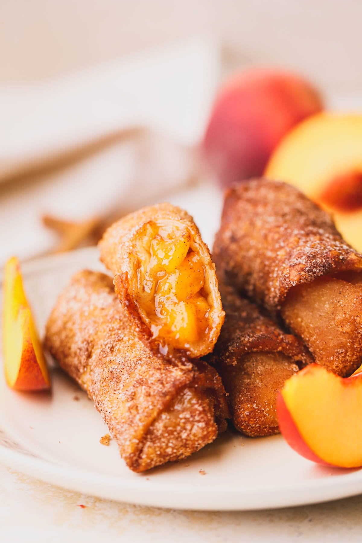 Peach cobbler egg rolls made with fresh peaches and dusted with cinnamon sugar.