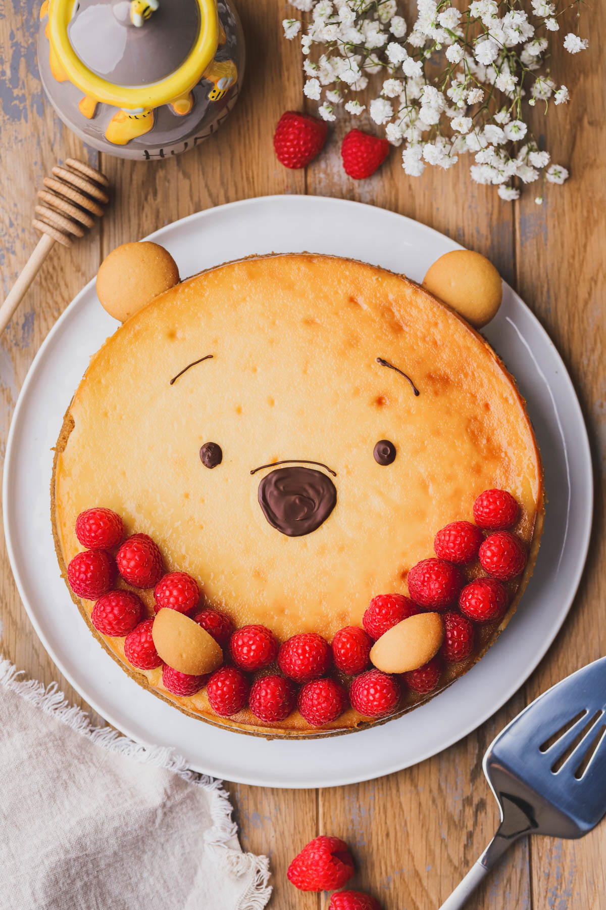 Creamy honey cheesecake with fresh raspberries and decorated as Winnie the Pooh.  