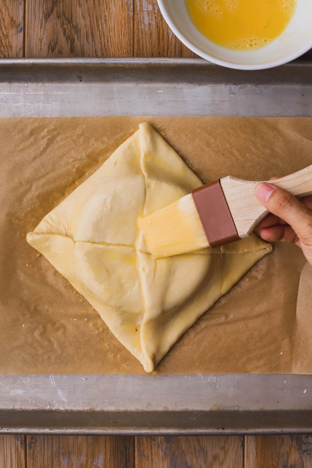 Egg wash over sealed brie in puff pastry.