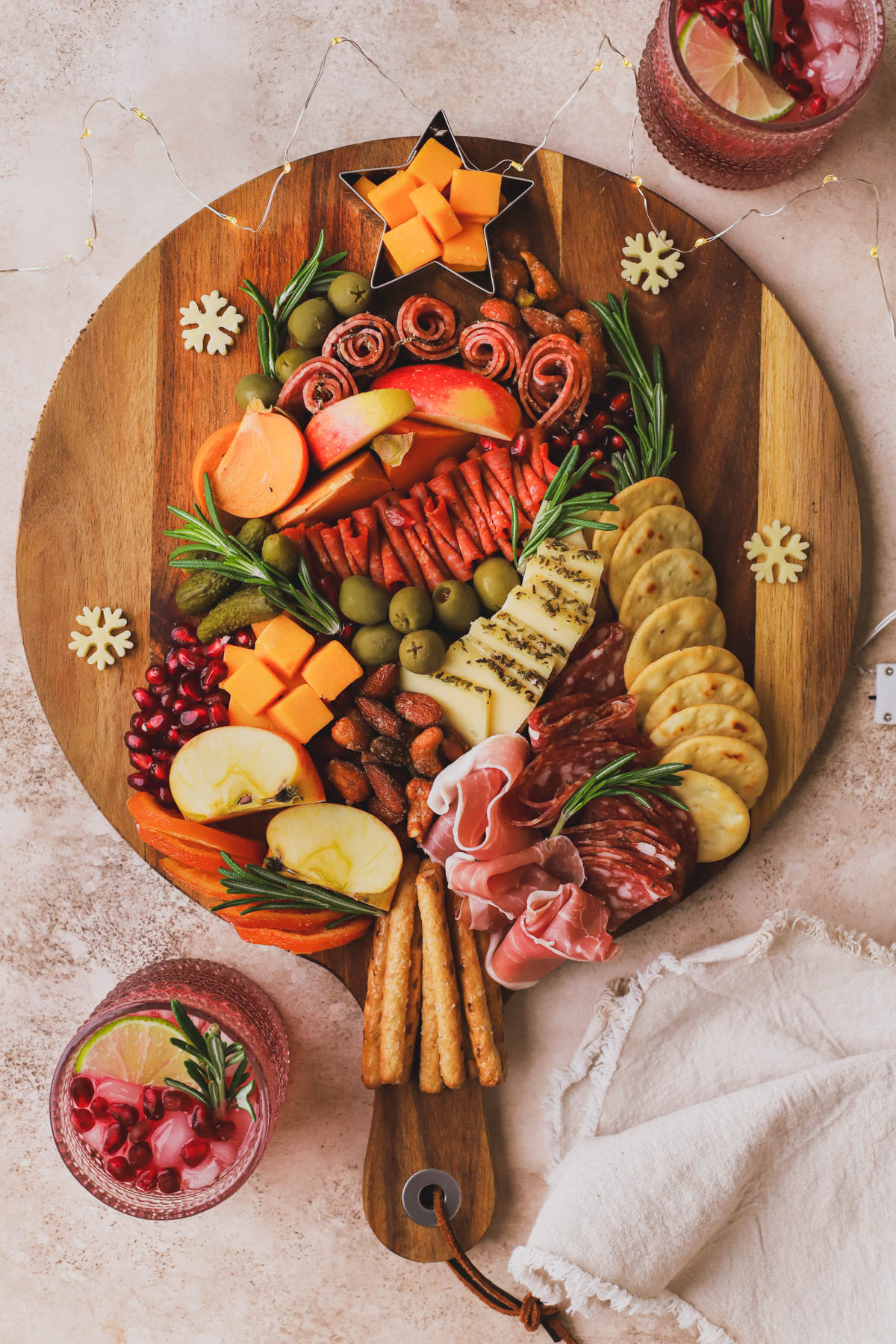 This charcuterie Christmas tree is made with cured meats, cheeses, olives, persimmons, apples, crackers and fresh rosemary.  