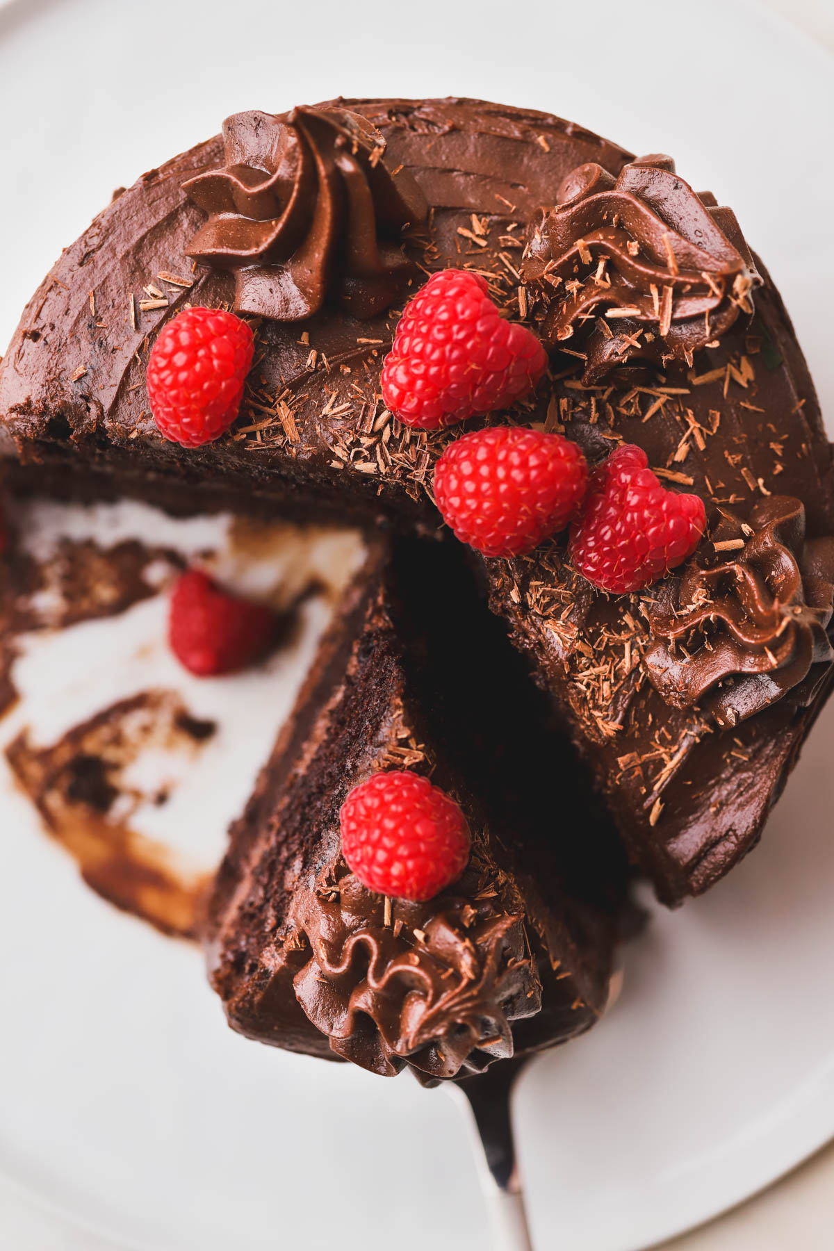 Top view of chocolate cake with chocolate frosting, shaved chocolate and fresh raspberries.  