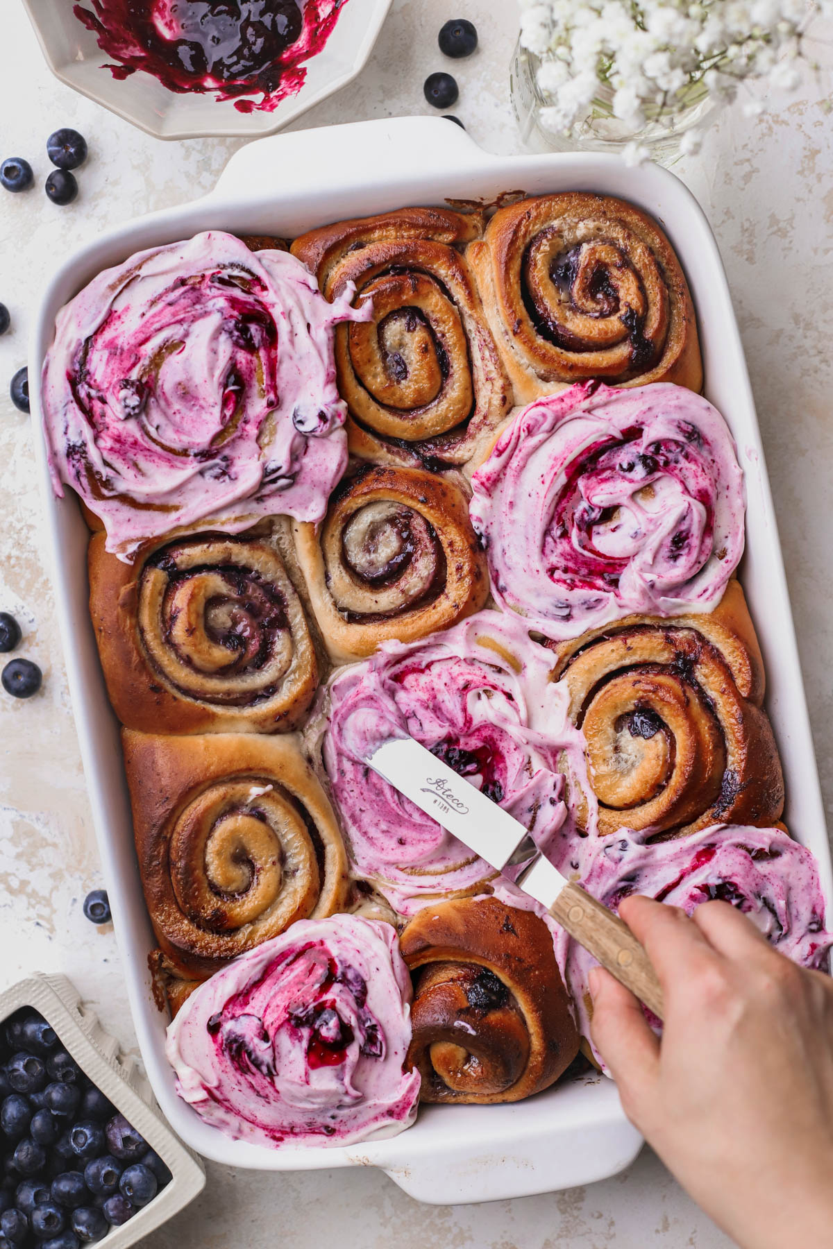 Baked cinnamon rolls with blueberry and blueberry cream cheese frosting. 