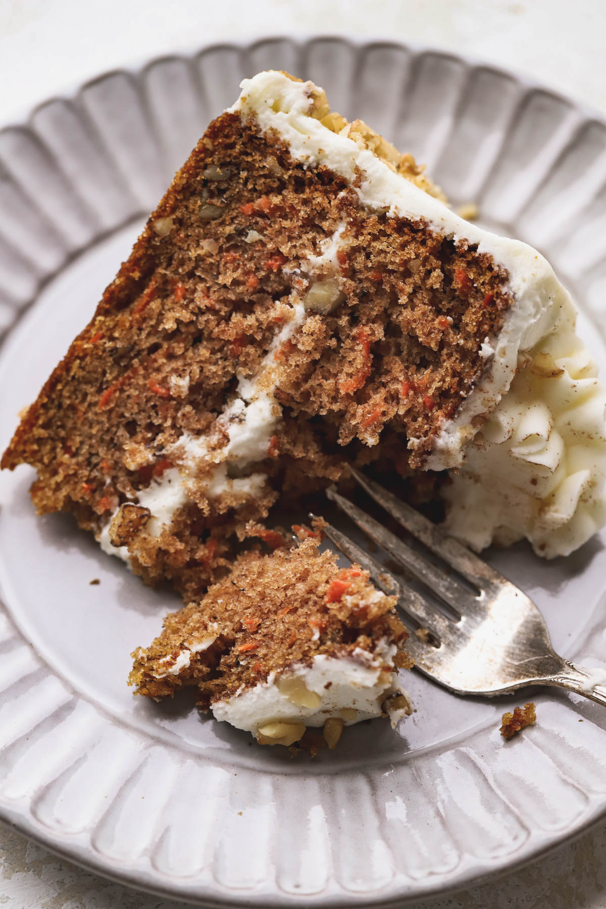 Slice of carrot cake with walnuts and cream cheese frosting.  