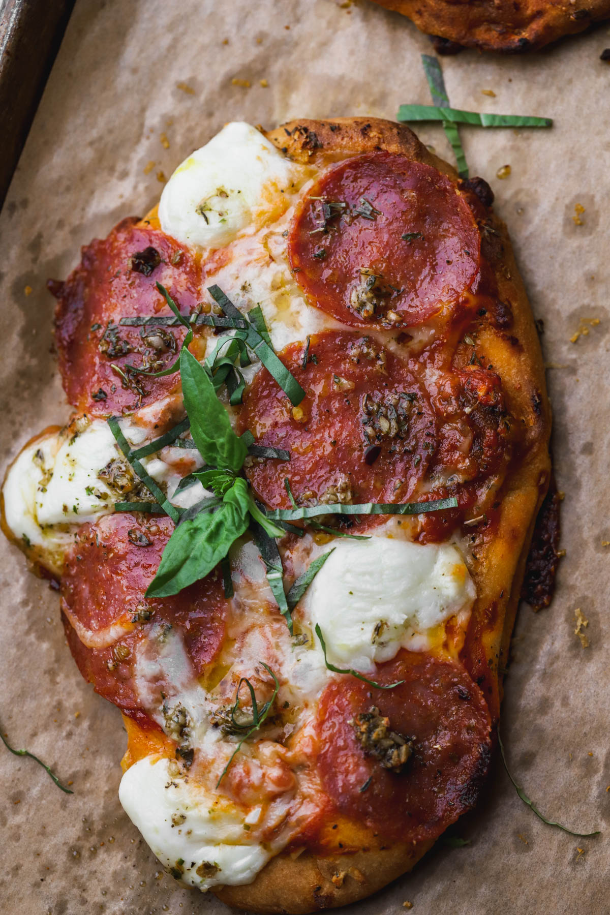 Pepperoni flatbread pizza with fresh basil, mozzarella and parmesan cheese. 