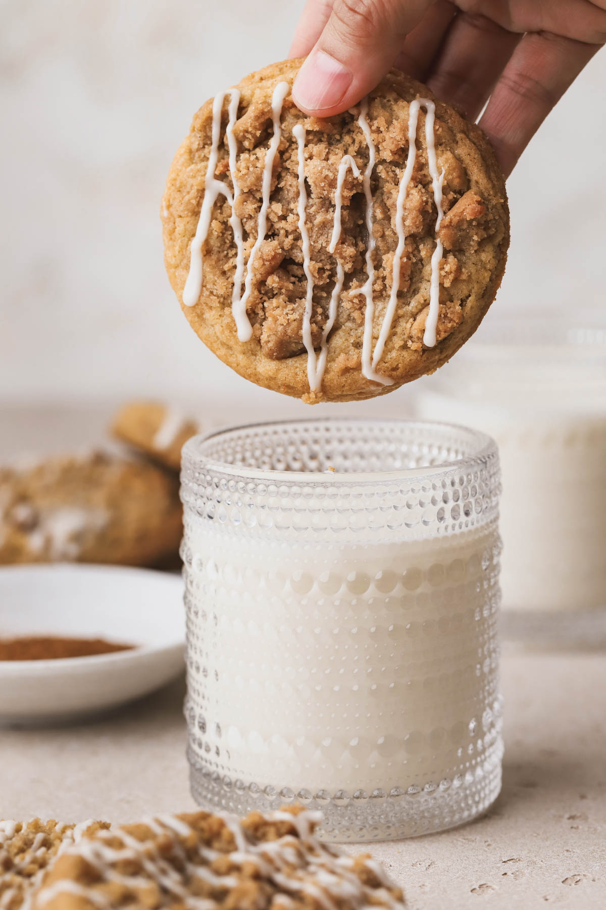 Coffee cake cookies with icing, dipped in glass of milk. 