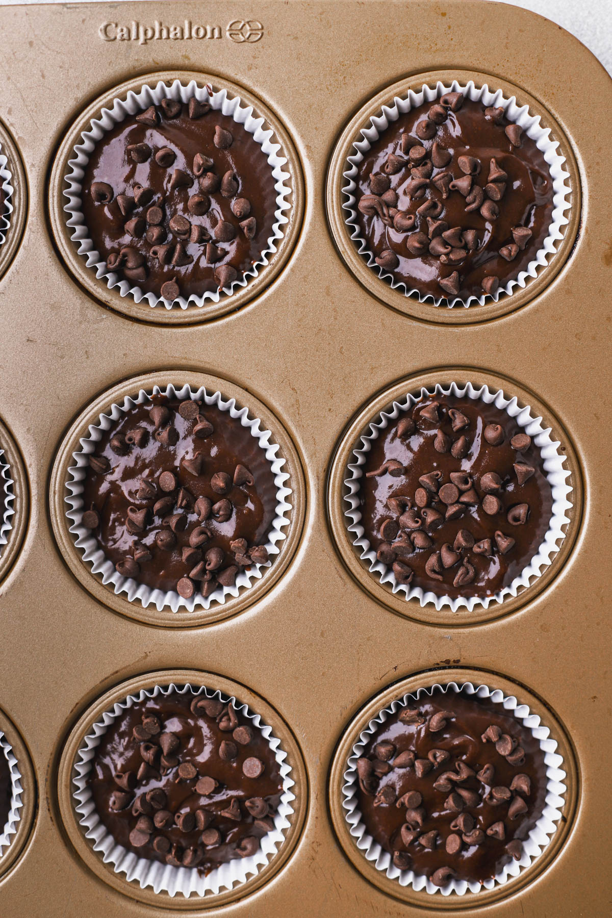 Muffin batter inside cupcake liner with mini chocolate chips. 