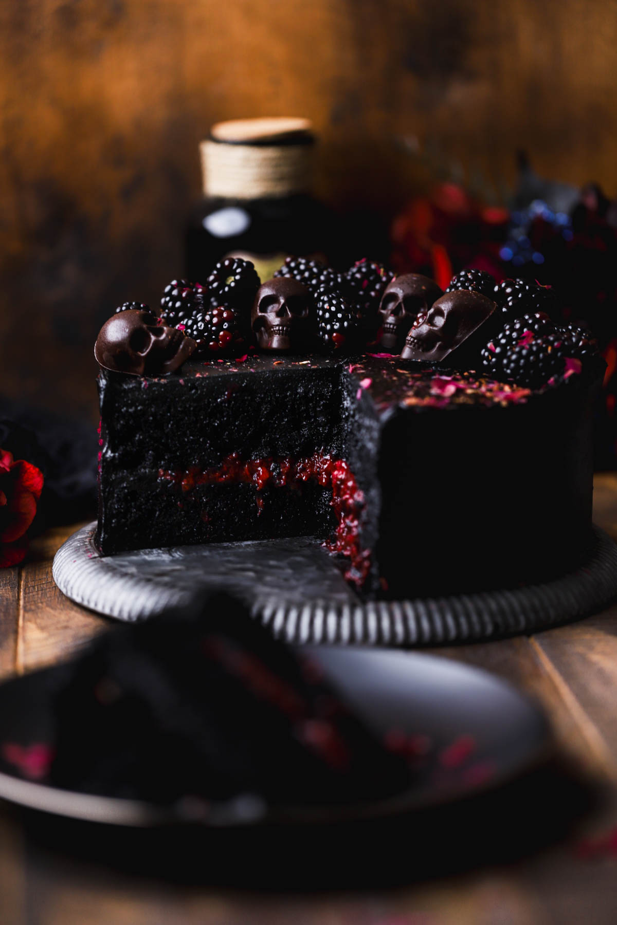 Black velvet halloween cake with fresh blackberry compote, chocolate skulls and dried rose petals.  
