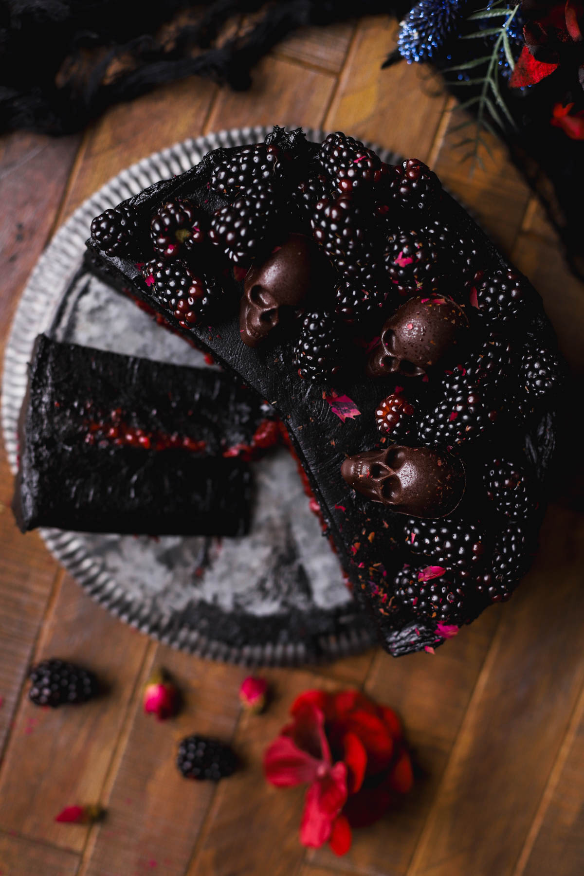 Black velvet halloween cake with blackberries, chocolate skulls and black cocoa powder buttercream. 