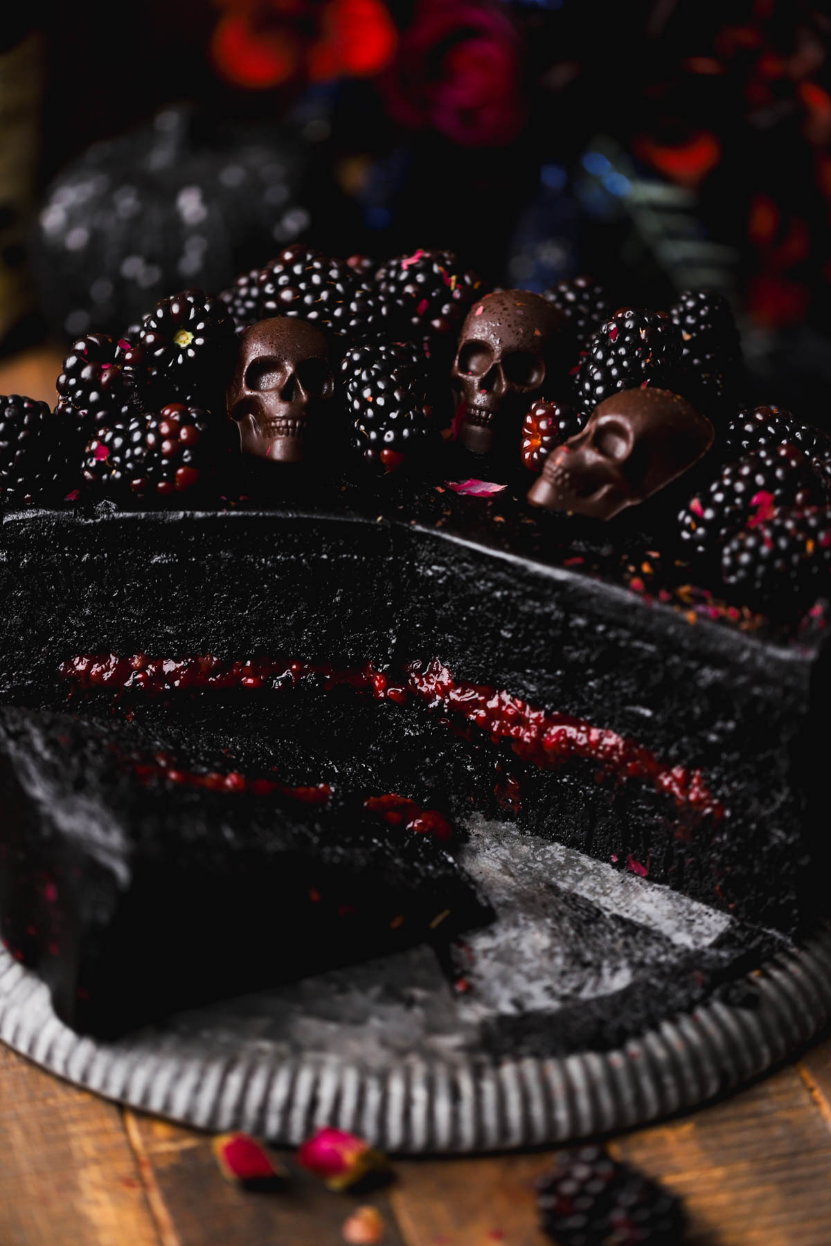 Two layers of black velvet cake, filled with blackberry compote and frosted with black cocoa buttercream.  Topped with chocolate skulls and blackberries.  