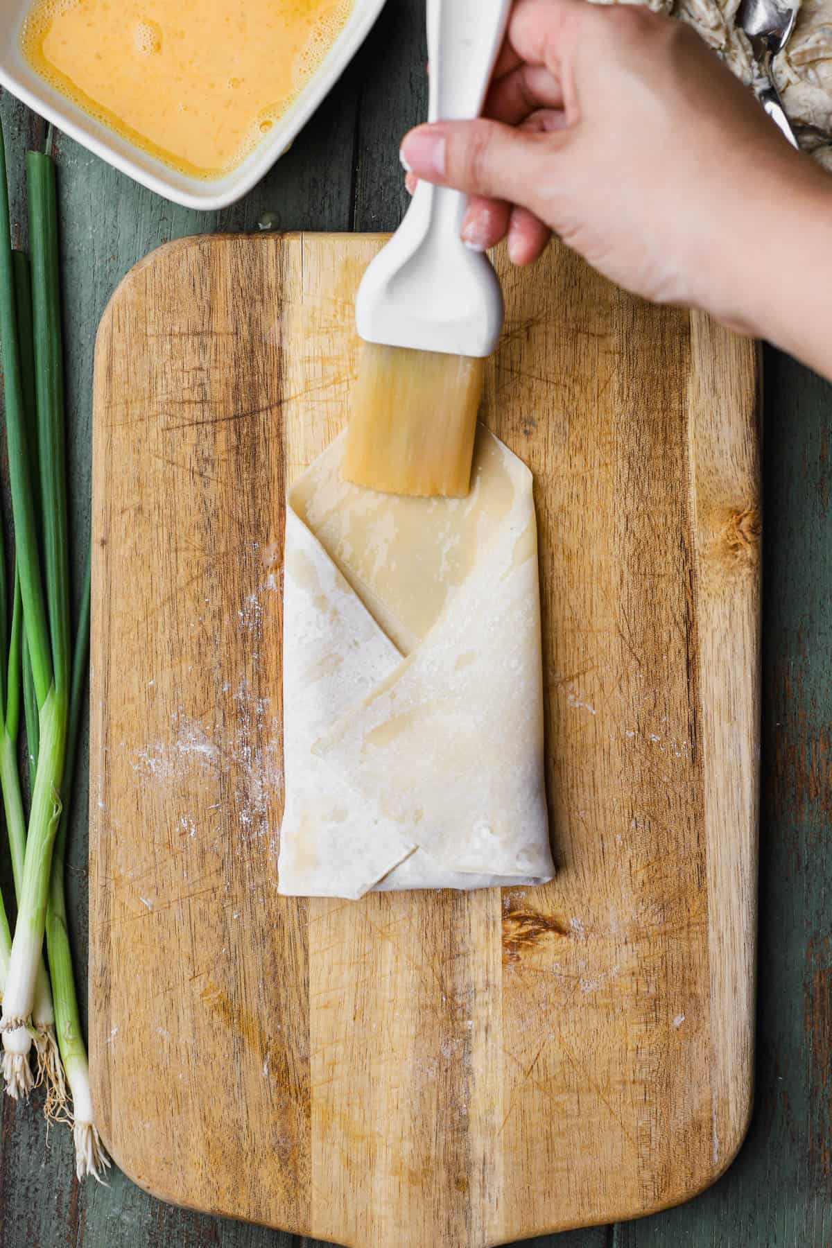 Brushing egg roll wrapper with egg wash. 