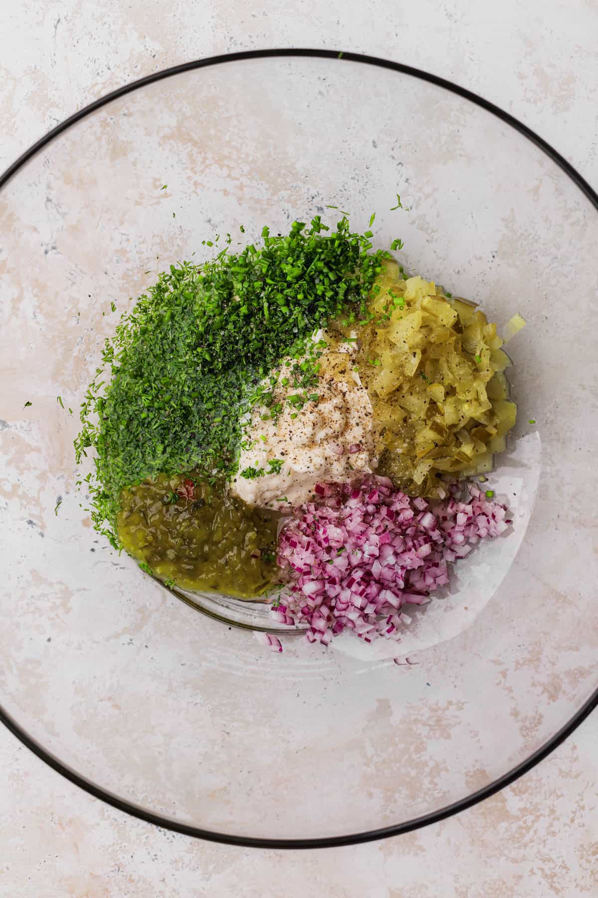 Mayo, sweet relish, dijon mustard, red onions, pickles, pickle juice, dill, chives, and celery seed.