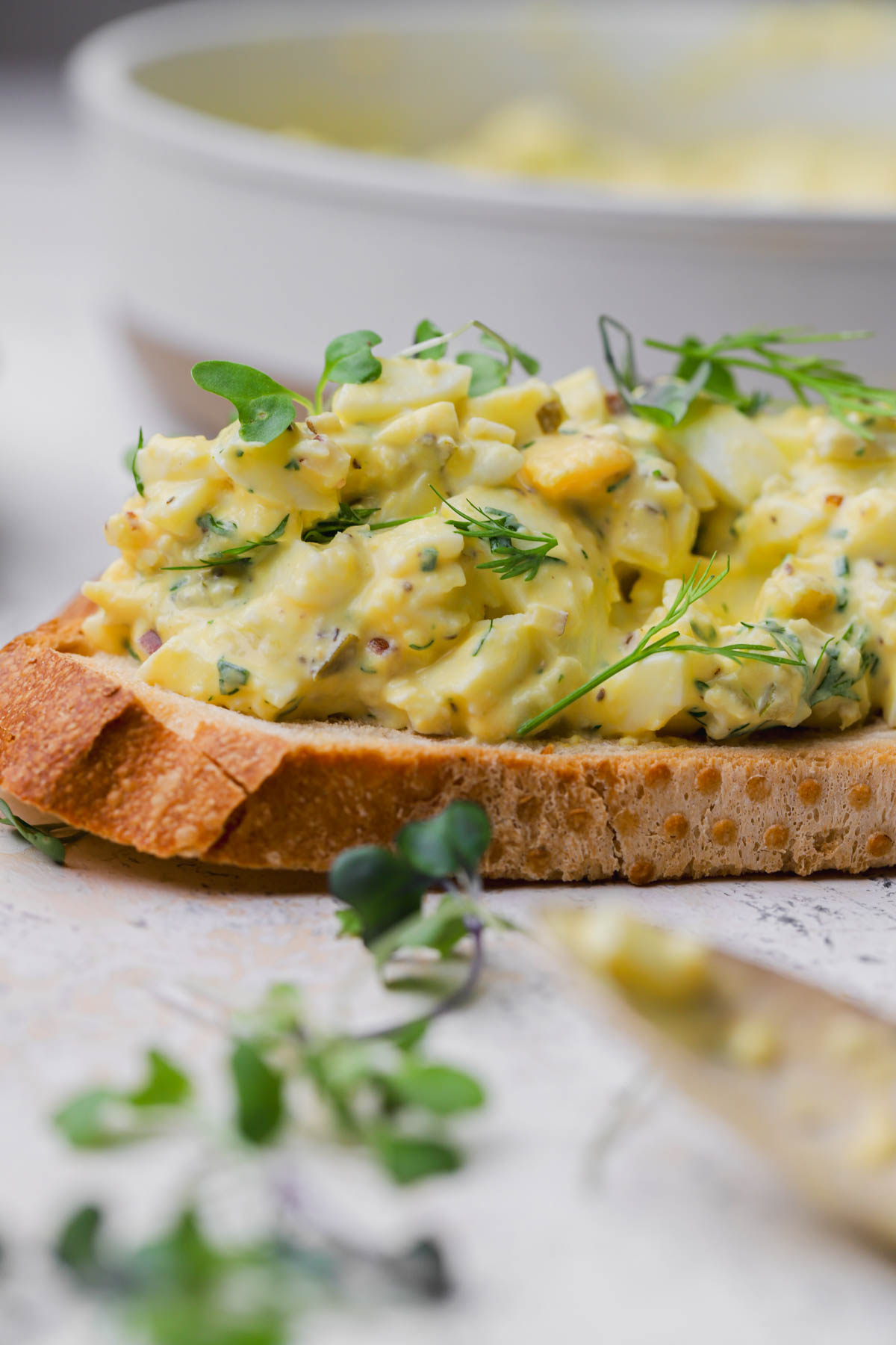 Egg salad with herbs, dill pickles, onion, mustard, and toasted bread. 