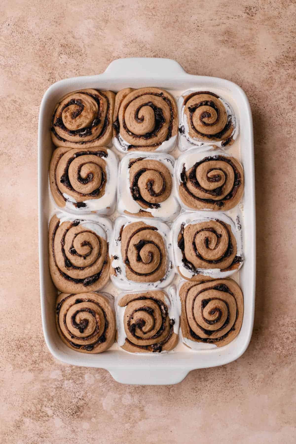 Heavy cream poured over risen cinnamon rolls.