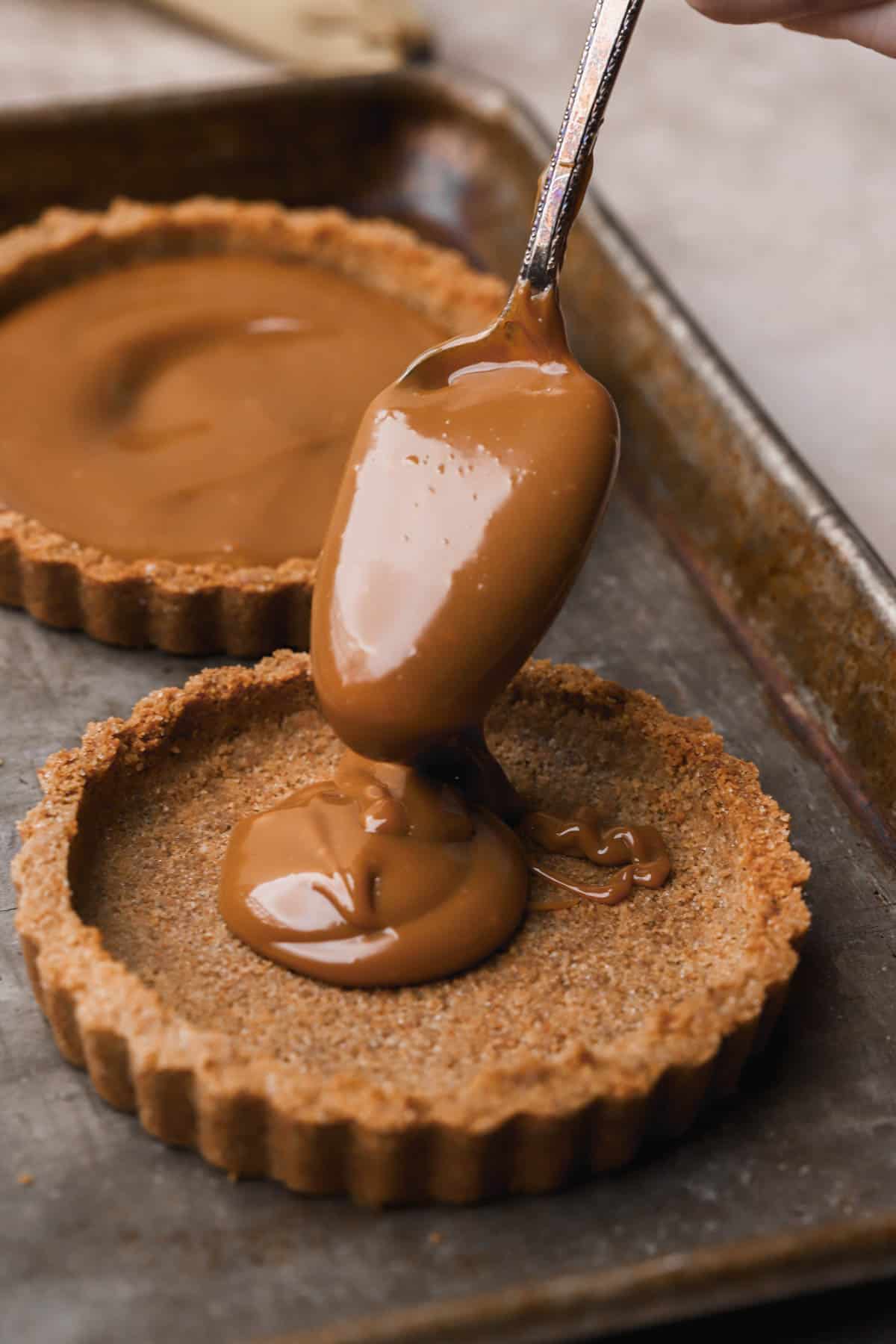 Dulce de lech spooned into graham cracker crust.