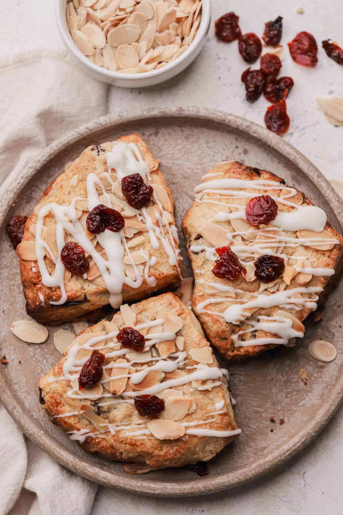 Almond cherry scones with sliced almonds and powdered sugar glaze.