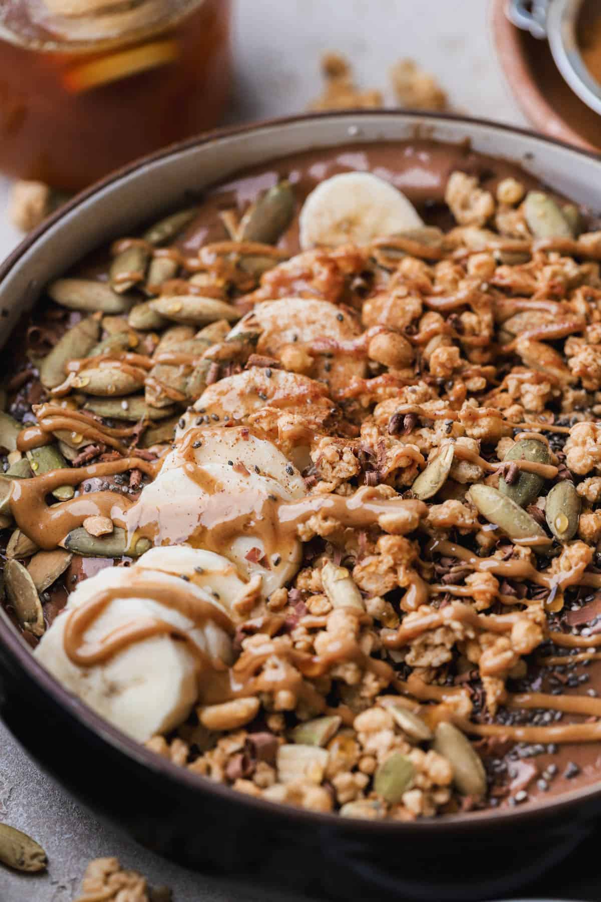 Chocolate smoothie bowl with bananas, pumpkin seeds, granola, chia and cinnamon. 
