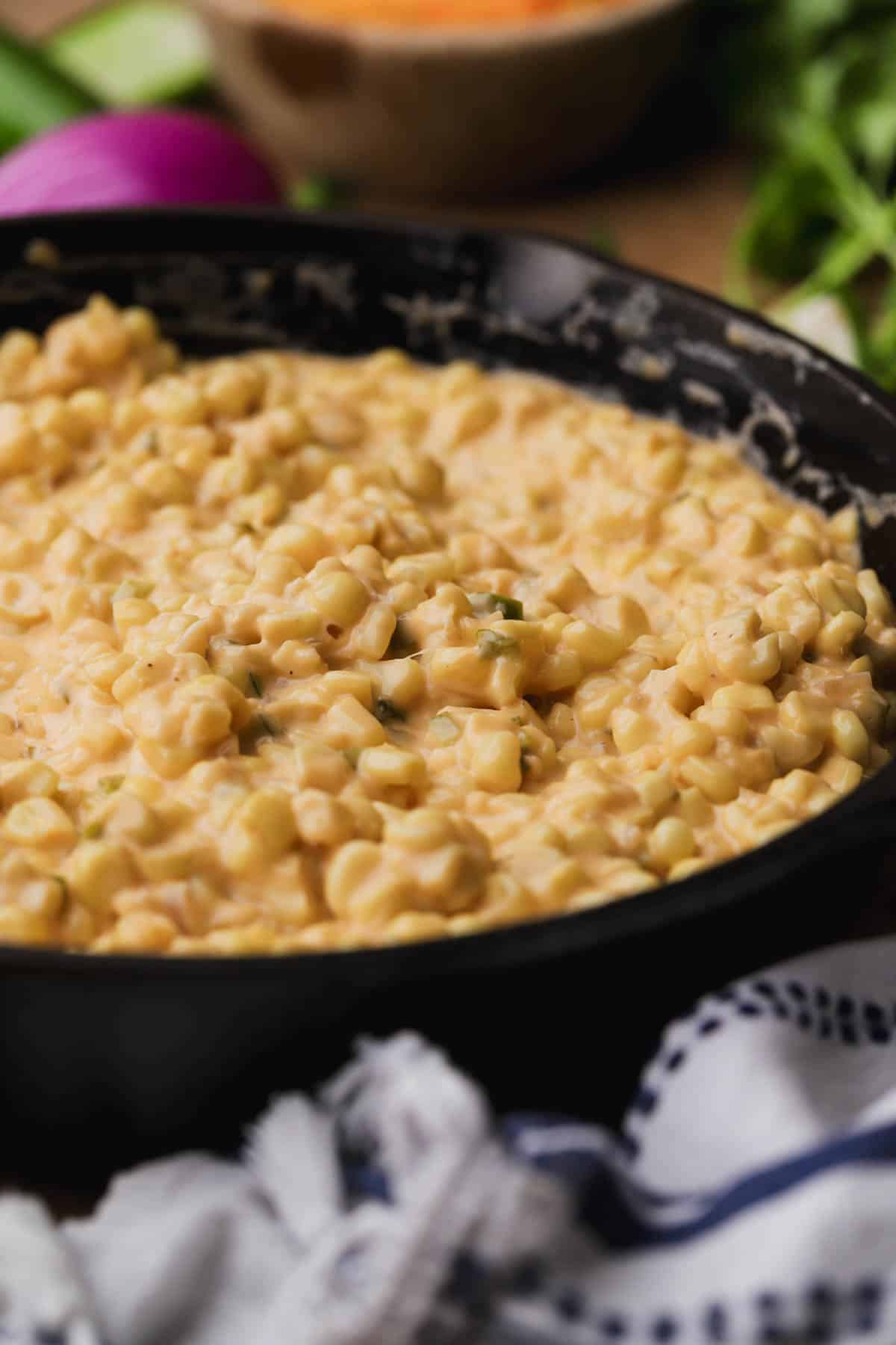 Corn with cream cheese, cheddar cilantro and red onions. 