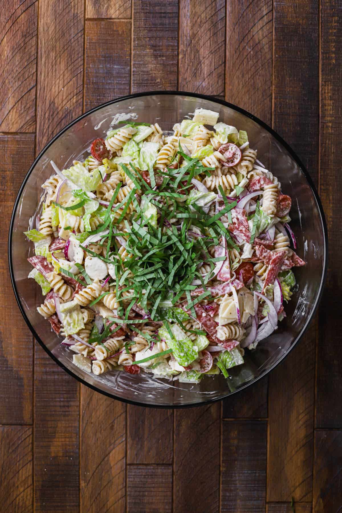 Pasta salad with cheese, salami, pepperoni, basil, lettuce, red onions, tomatoes and creamy dressing.