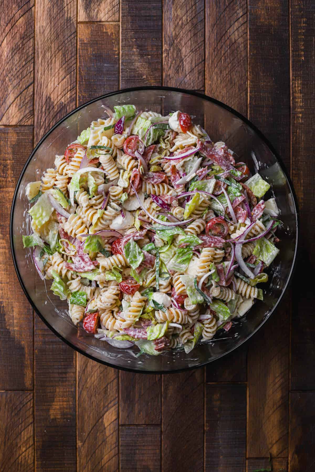Creamy pasta salad, with pepperoni, salami, cheese, lettuce, red onions, tomatoes, and romaine lettuce.