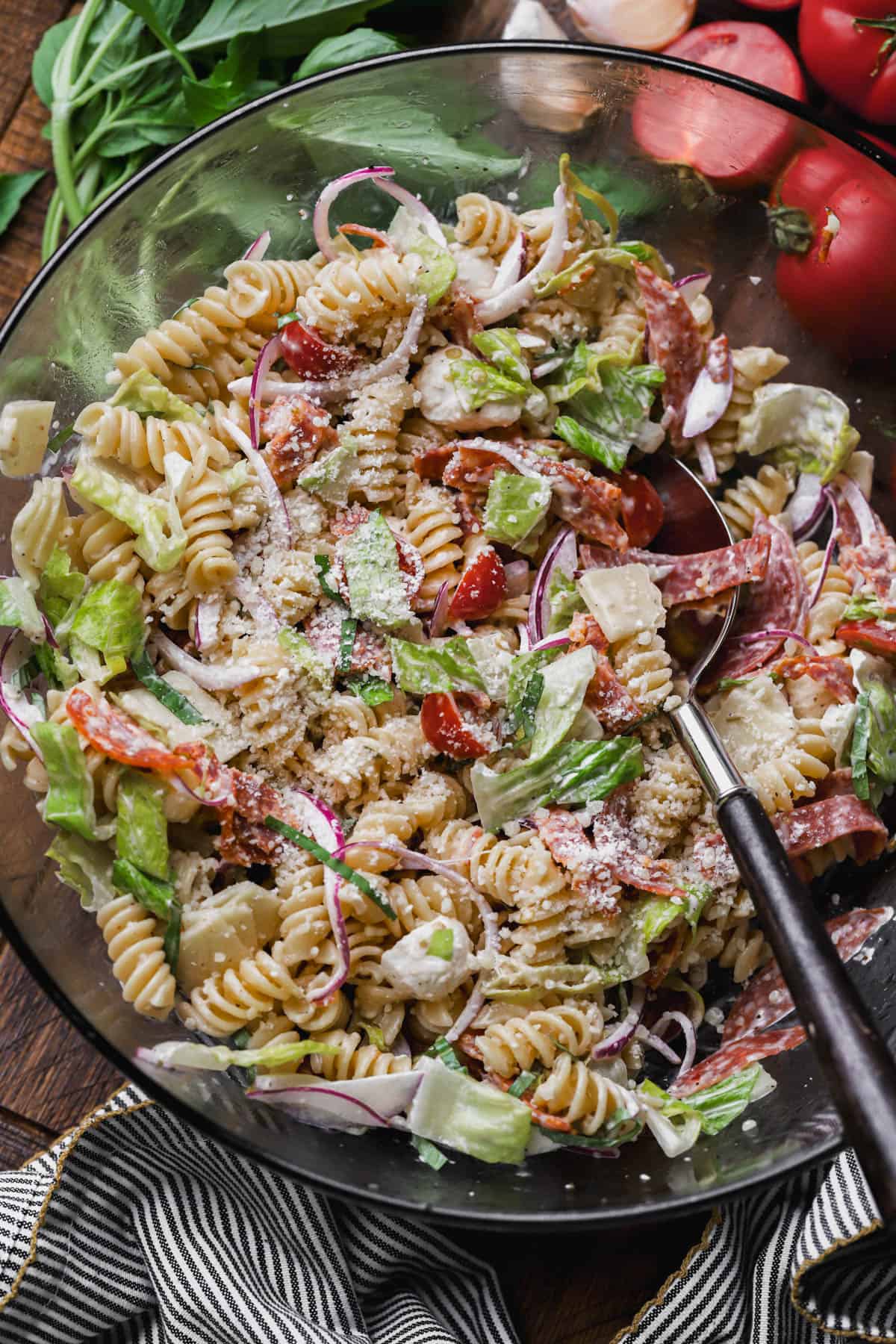 Grinder pasta salad with cheese, salami, pepperoni, parmesan, tomatoes, romaine lettuce, pepperoncini, and red onions.