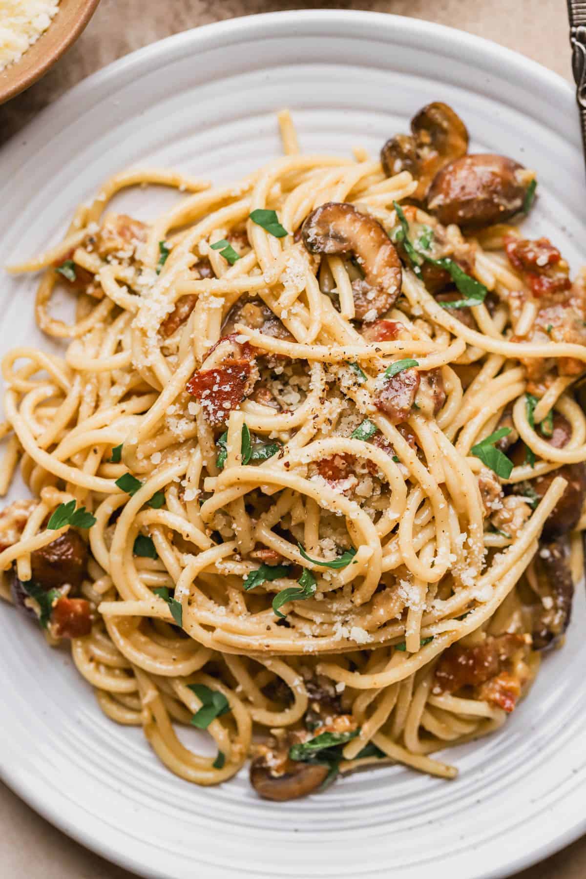 Bacon mushroom carbonara with garlic mushroom, parmesan, eggs, egg yolks, pecorino, black pepper and chopped parsley.