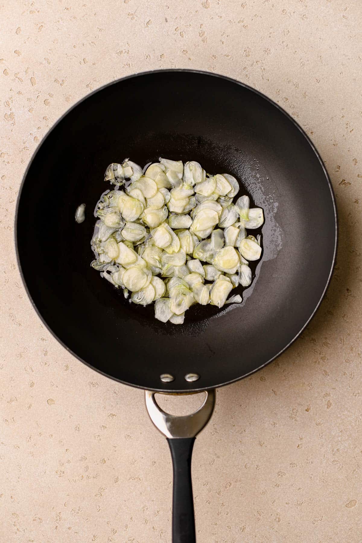 Sliced garlic cloves cooking in olive oil.
