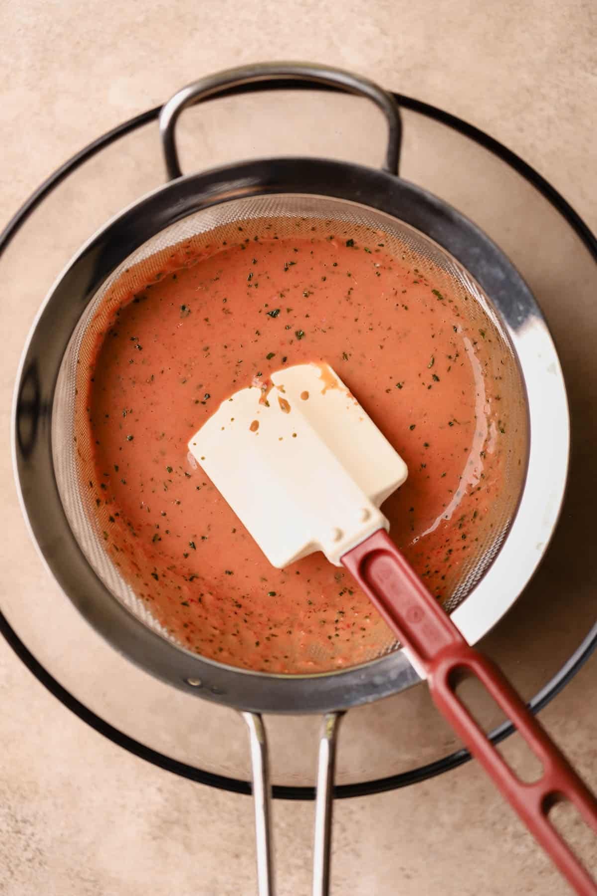Strawberry basil balsamic dressing strained through a fine-mesh sieve.