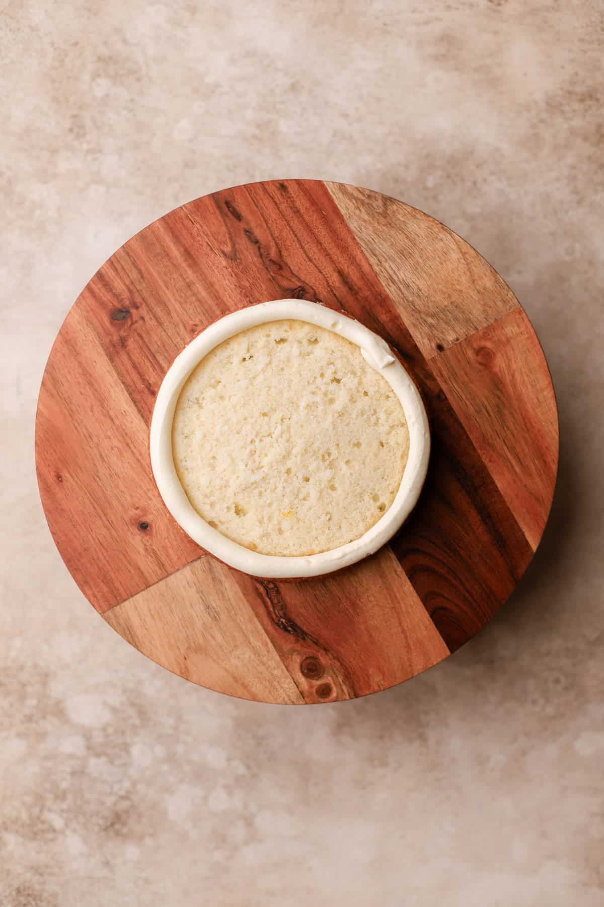 Piped cream cheese frosting along edges of coconut cake. 