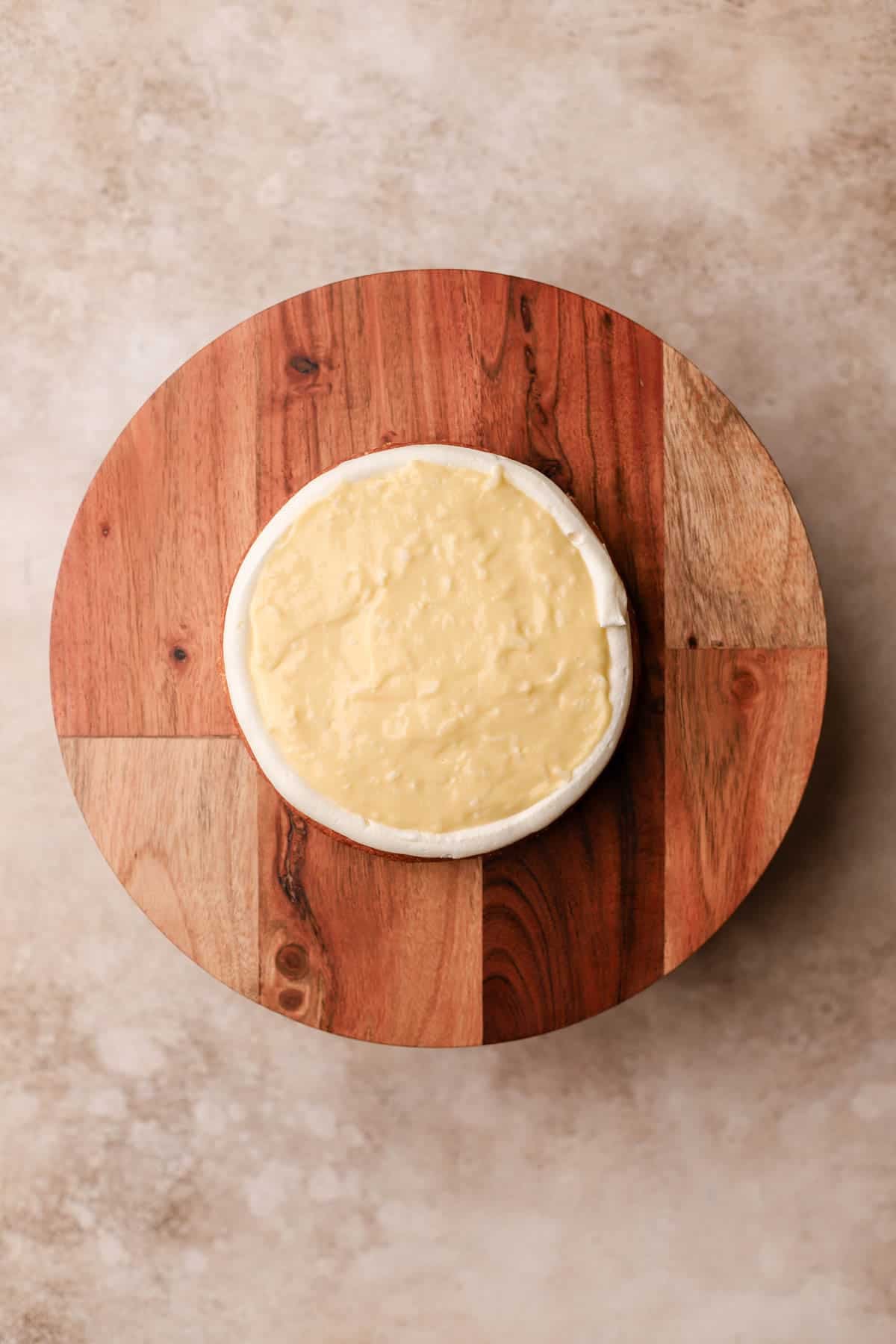 Piped cream cheese frosting along edges of coconut cake, filled with coconut pastry cream. 