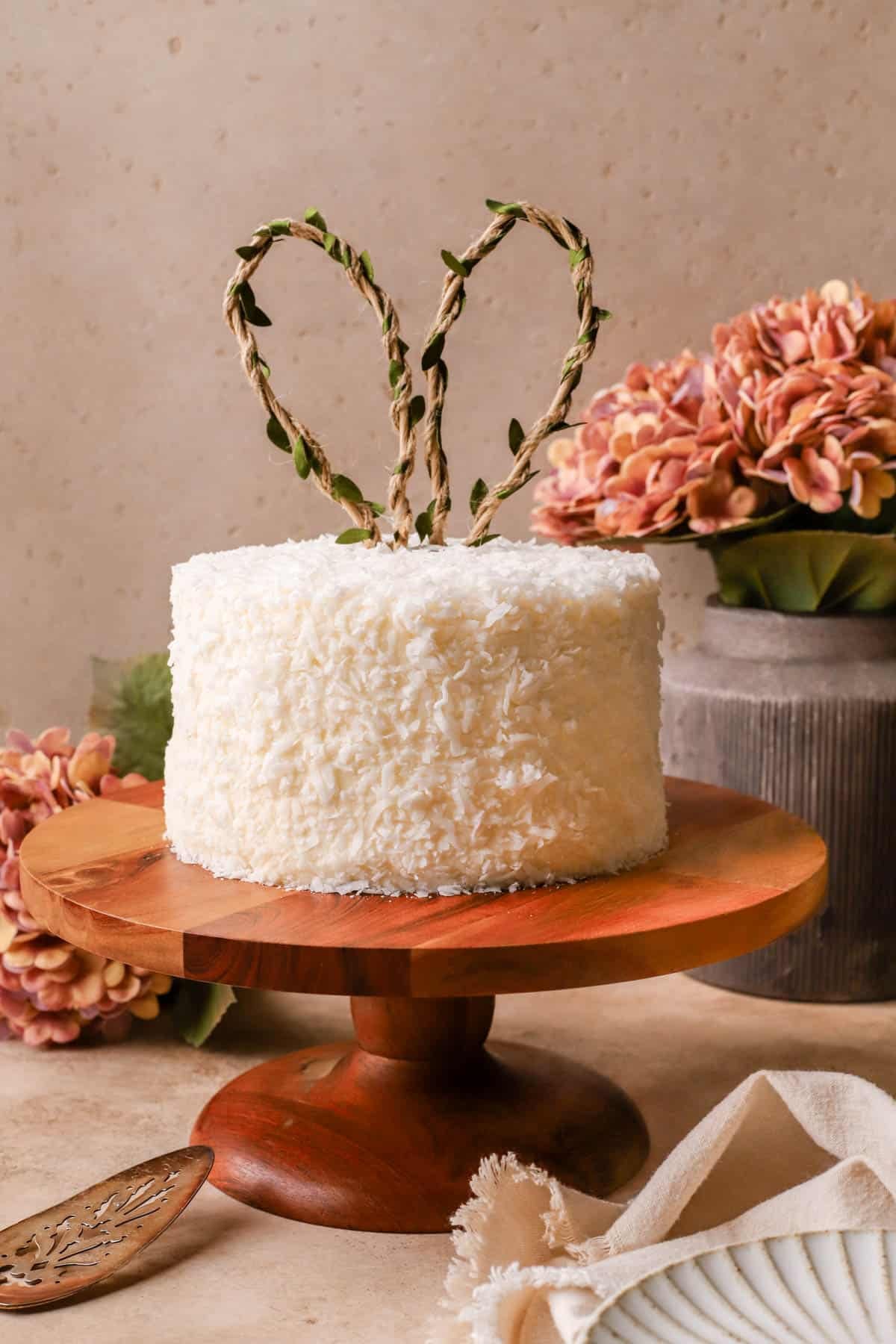 Coconut Layer Cake filled with pastry cream, covered in cream cheese frosting, shredded coconut, and topped with cute bunny ears. 