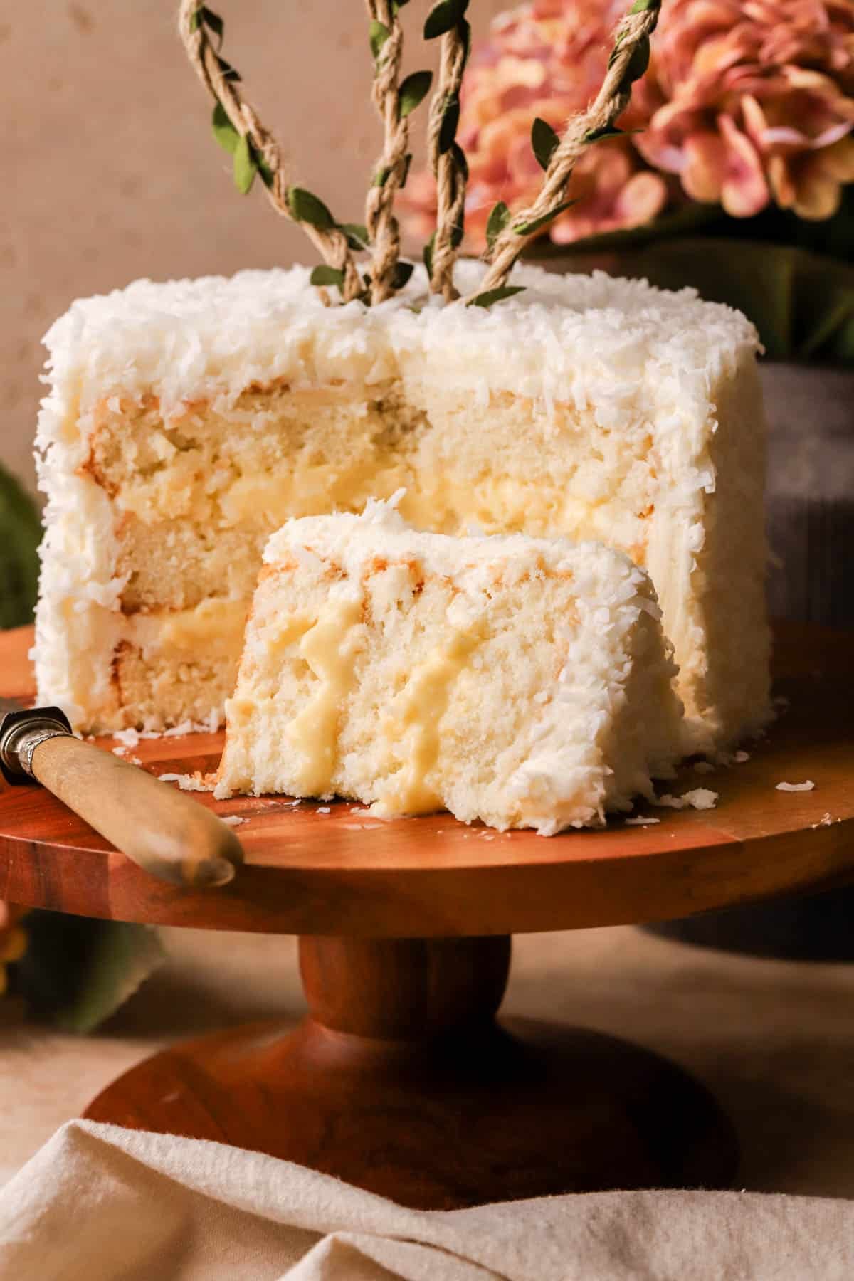 Coconut layer cake filled with pastry cream and coated in cream cheese frosting and shredded coconut. 