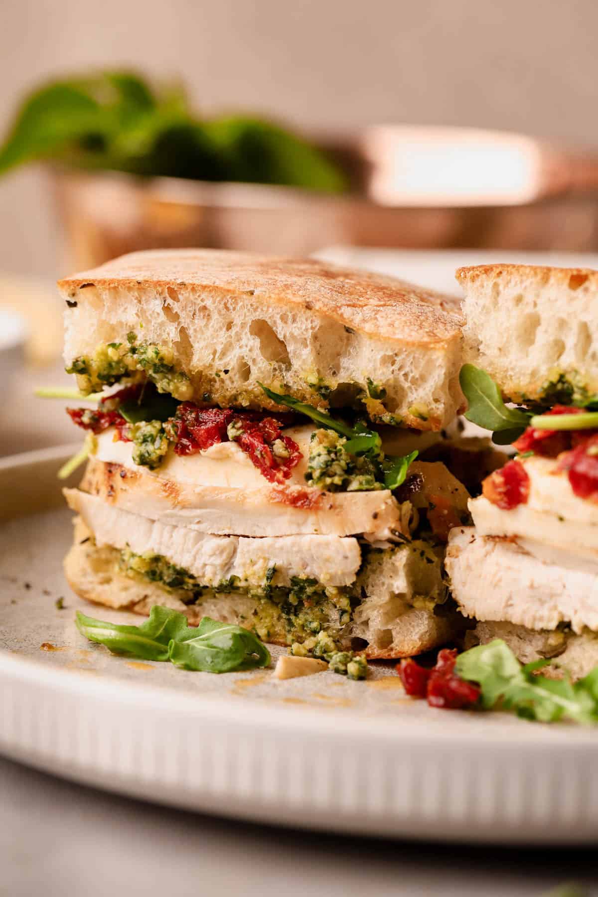 Sun-dried tomato pesto chicken sandwich with herb focaccia, fresh mozzarella slices, and fresh arugula.