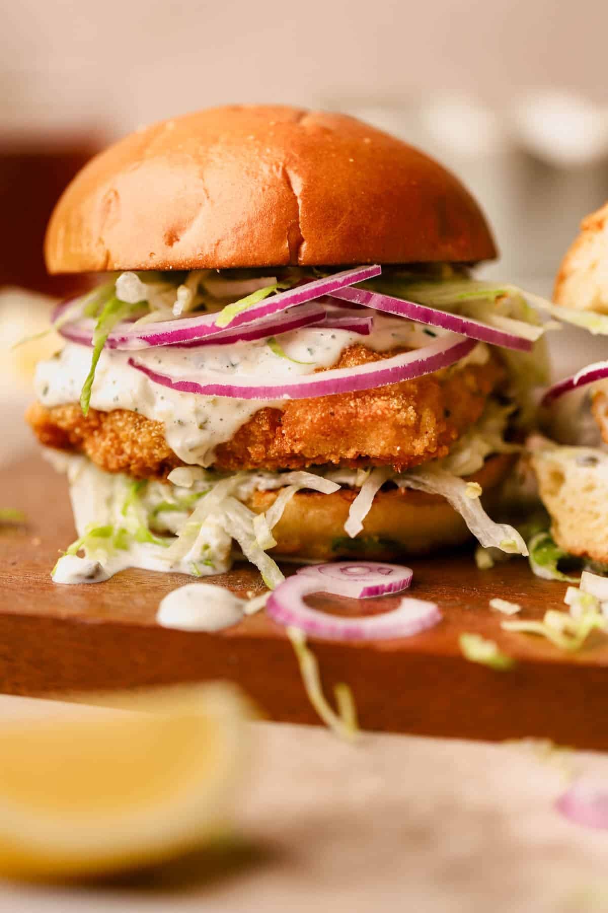 Crispy cod sandwich is dredged in a cornmeal and breadcrumb mixture and pan-fried until crisp and golden.  Served inside a toasted brioche bun with homemade tartar sauce, red onions, and shredded lettuce.  