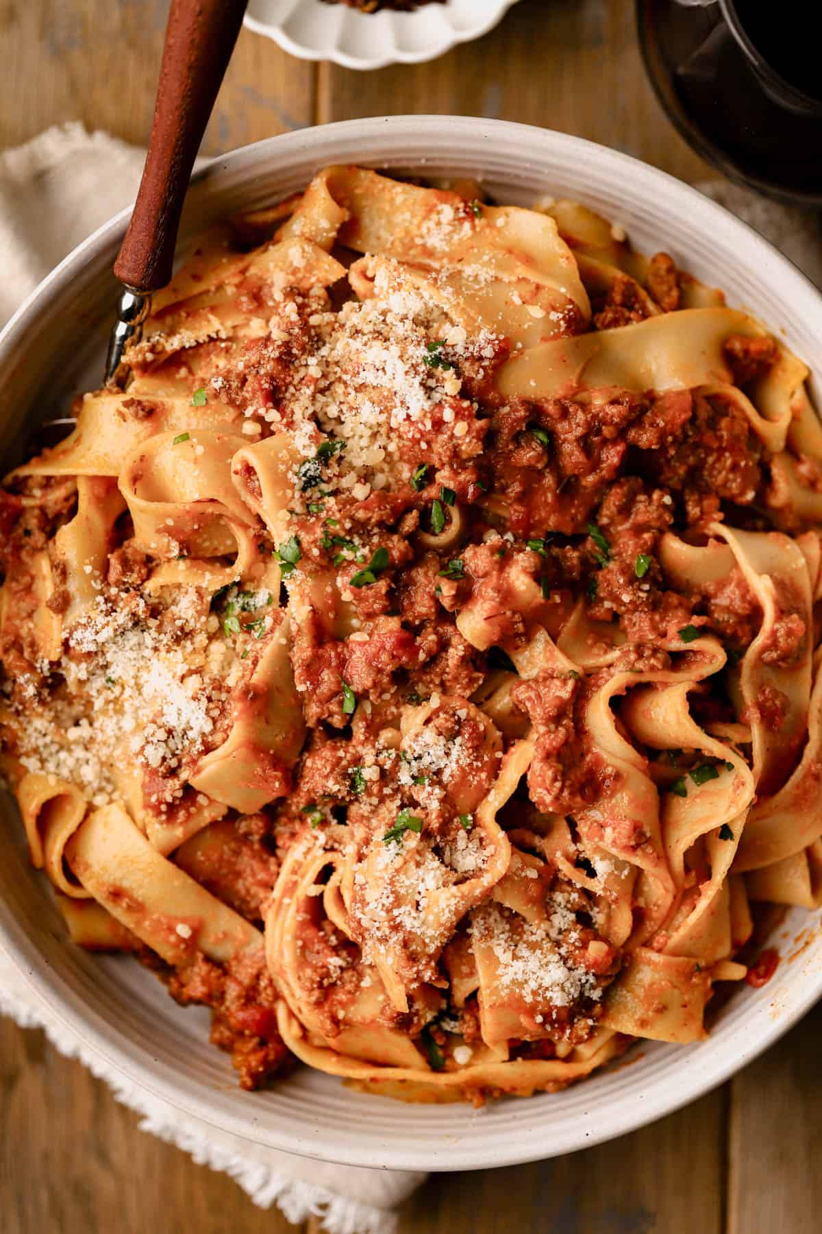 Spicy bolognese with pappardelle is made with ground beef, pancetta, spicy Italian sausage, red pepper flakes, fresh herbs, vegetables, tomatoes and red wine.  Served with pappardelle pasta and parmesan cheese.