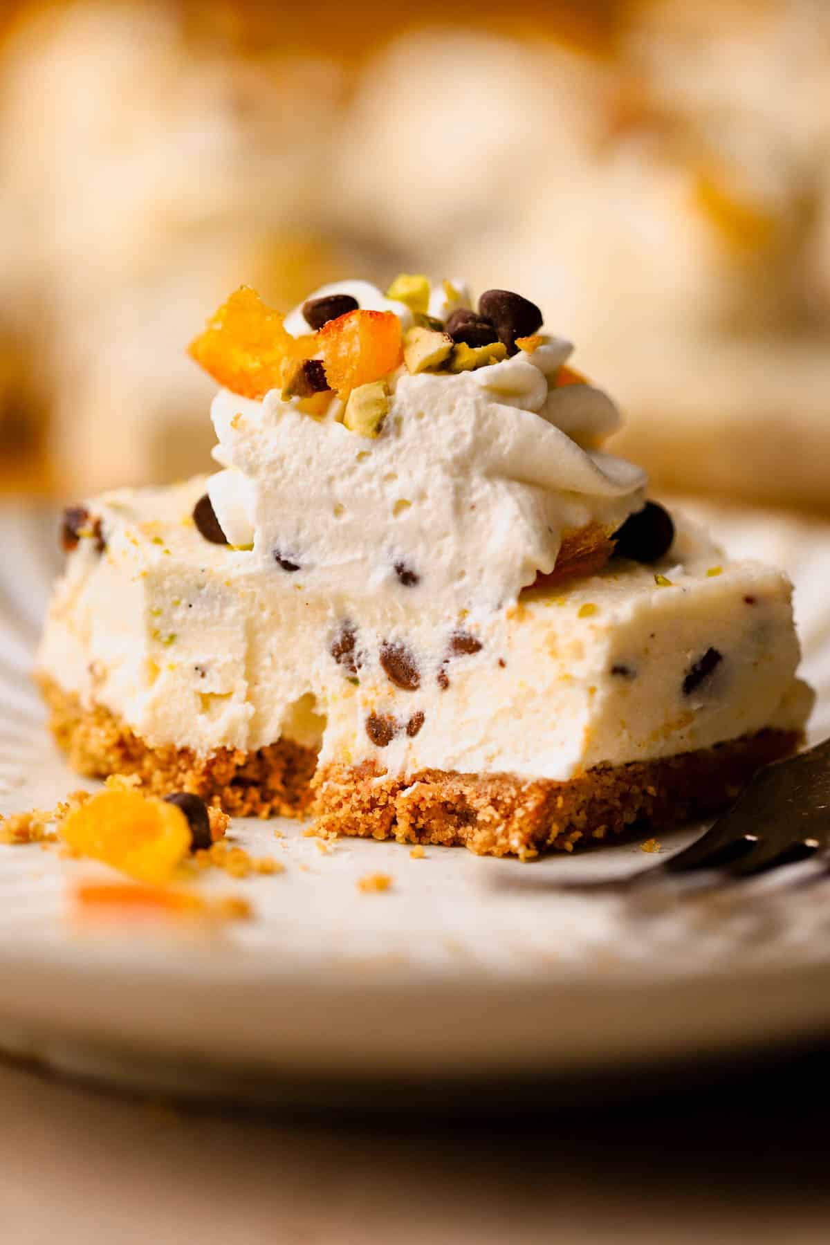 Cannoli bars are made with a graham cracker crust, ricotta, cream cheese, powdered sugar, vanilla bean paste, orange zest, mini chocolate chips, and chopped pistachios. 