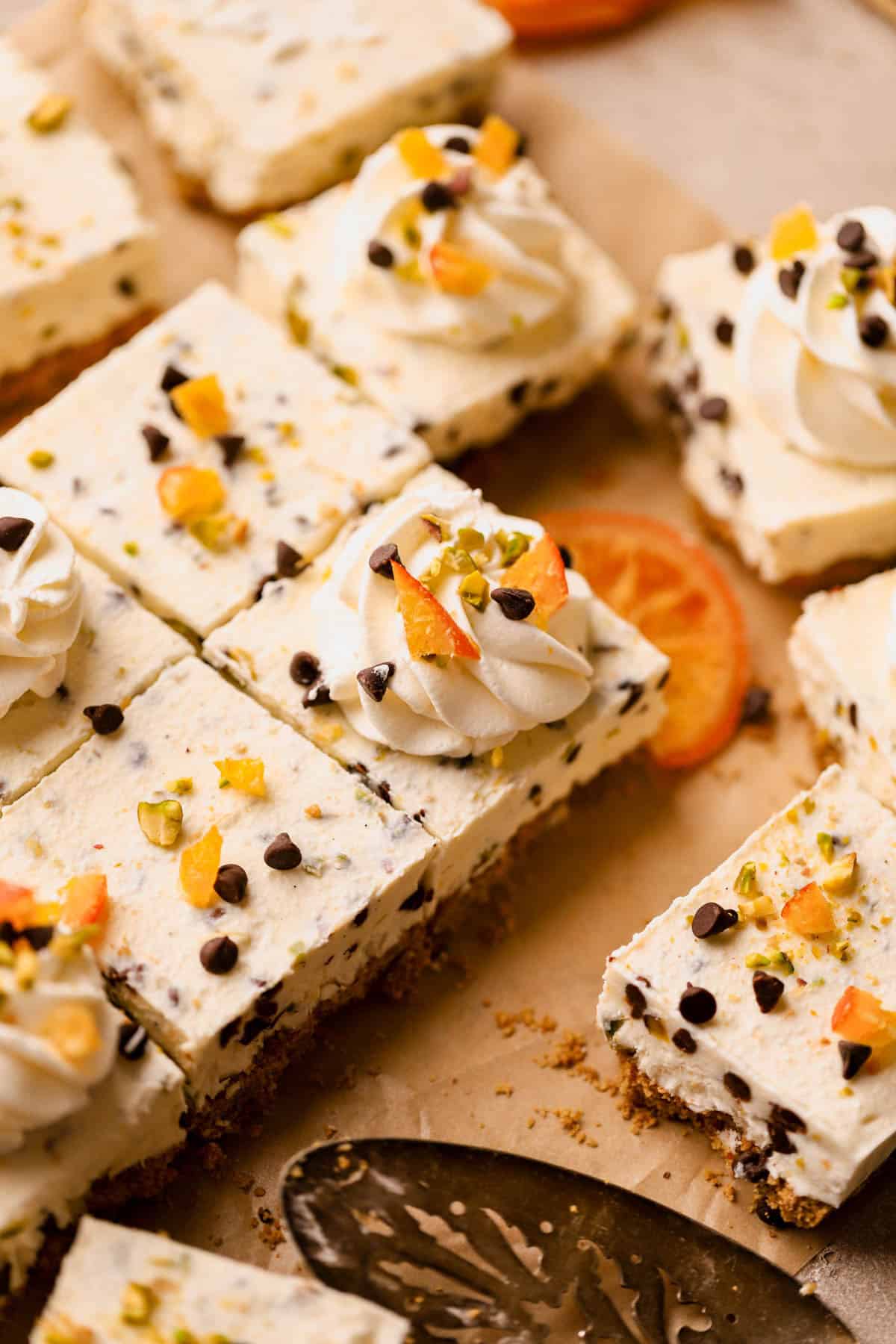 Cannoli bars are made with a graham cracker crust, ricotta, cream cheese, powdered sugar, vanilla bean paste, orange zest, mini chocolate chips, and chopped pistachios. 