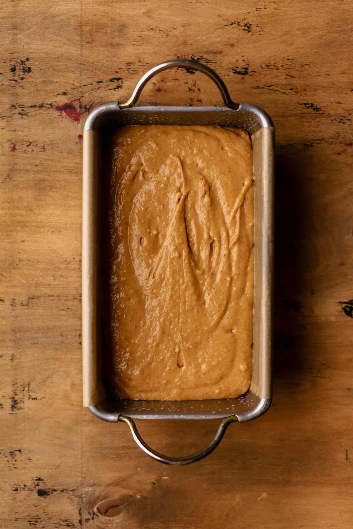 Pumpkin bread batter poured into greased, parchment lined 9x5 inch loaf pan.