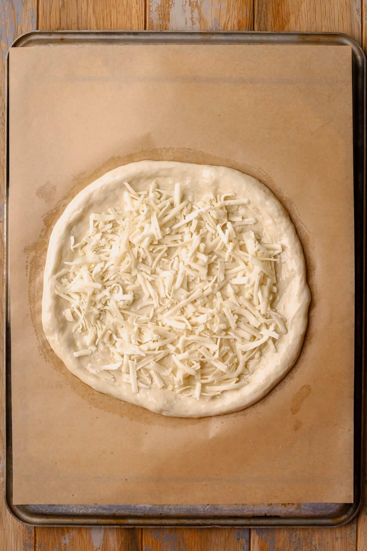 Store-bought pizza sough brushed with olive oil and sprinkled with fontina cheese.